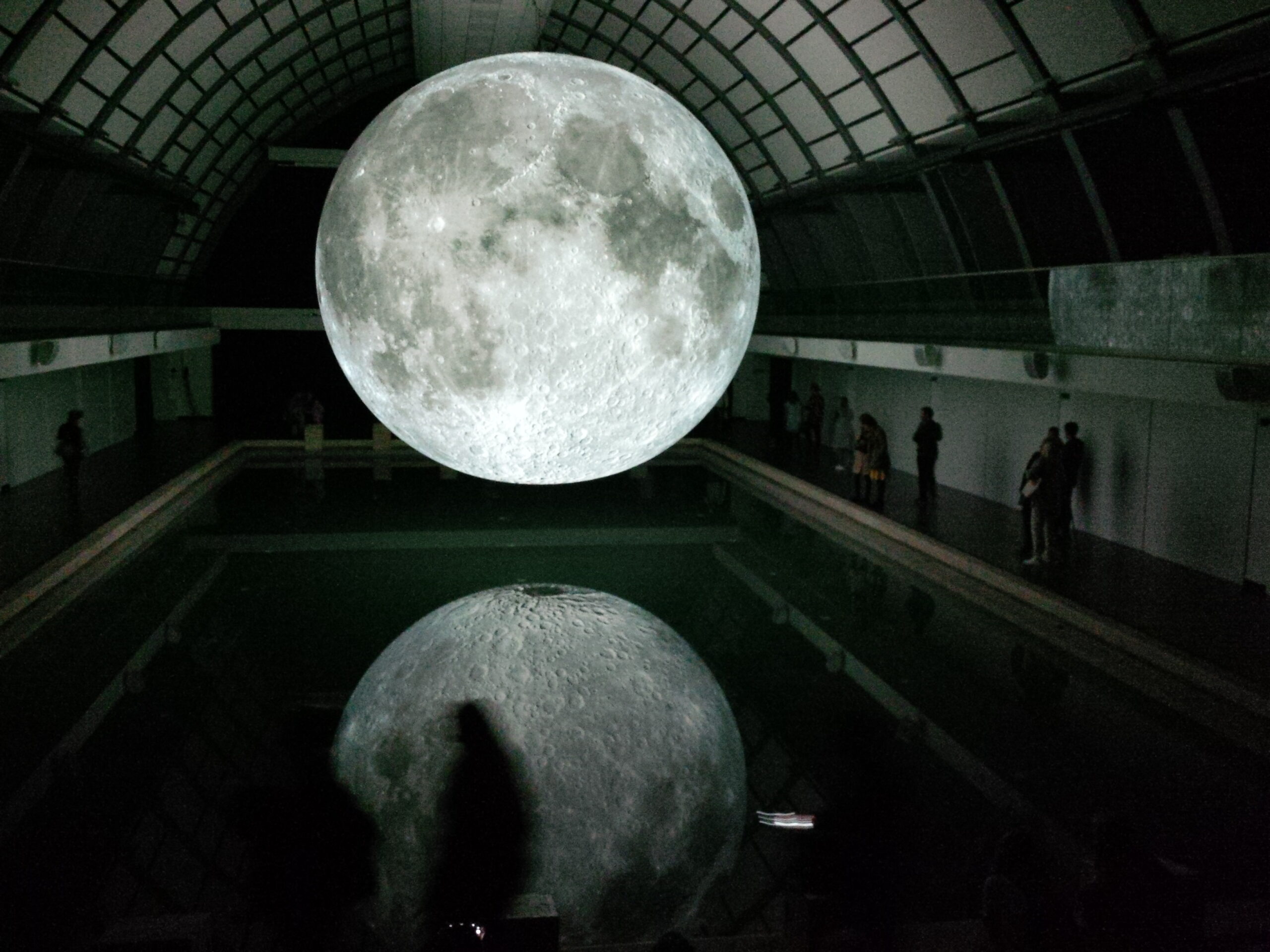 Photo of moon hologram floating on water near people inside room