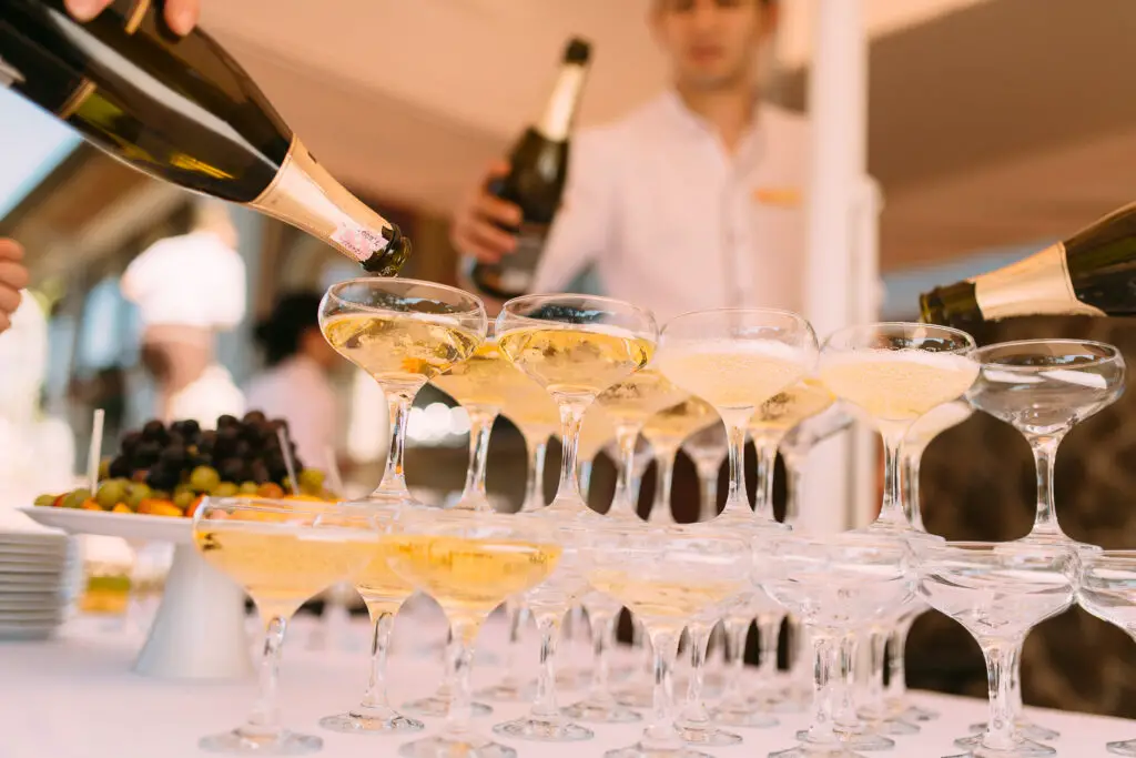 Person pouring liquor in cocktail glasses