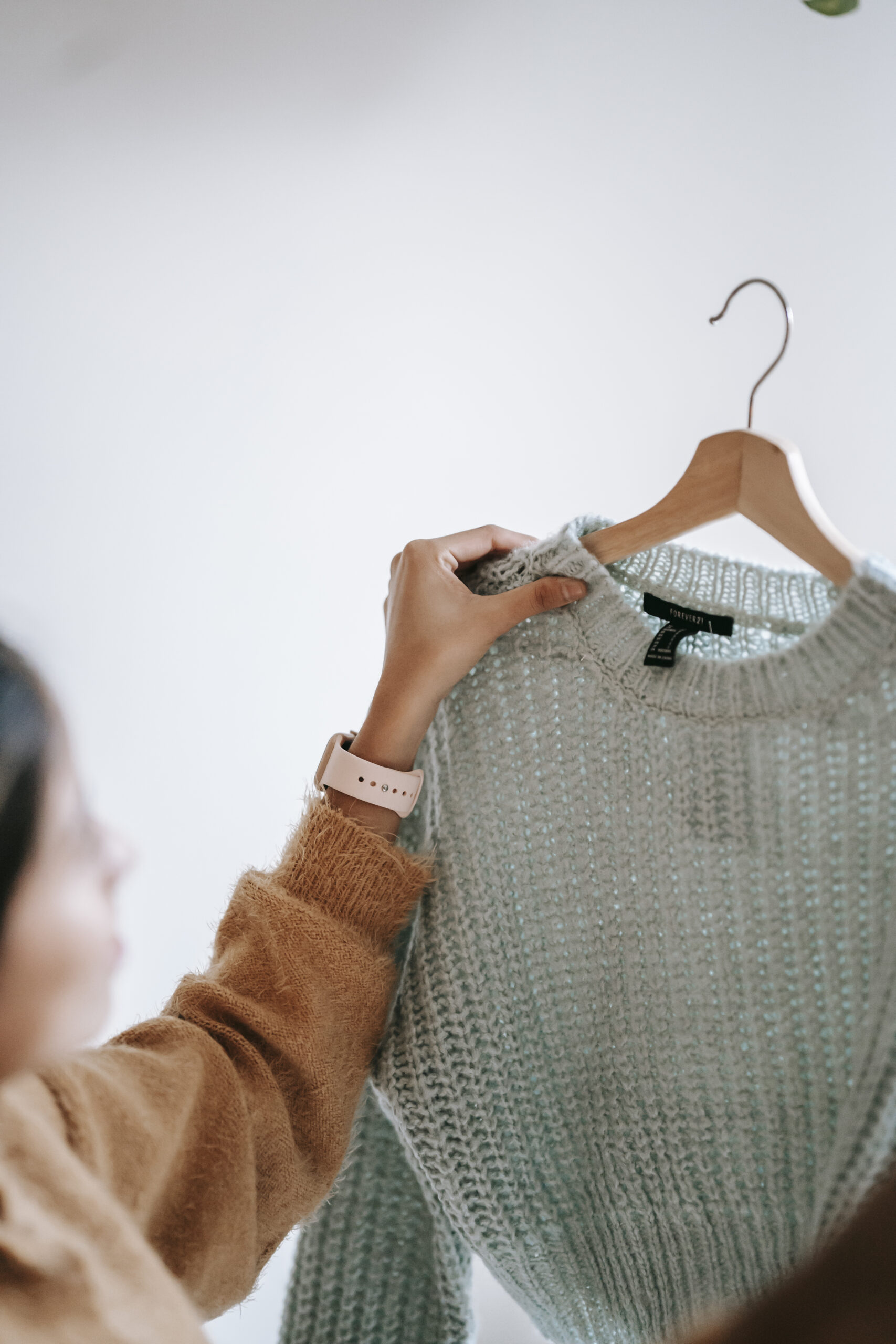 Crop woman with sweater on hanger