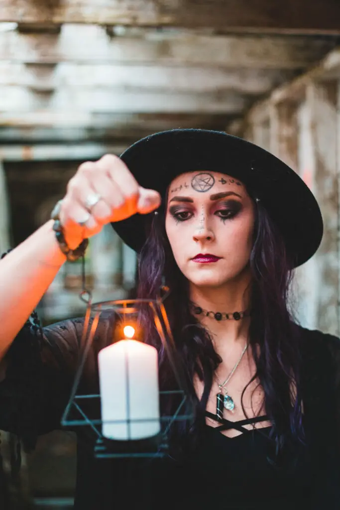 Woman in hat holding burning candle